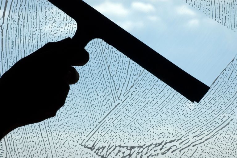 Ein Fensterputzer in Wuppertal reinigt das Glas einer Fensterscheibe